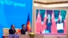 FILE - Vietnamese Prime Minister Nguyen Xuan Phuc, left, and Minister of Trade Tran Tuan Anh applaud next to a screen showing Chinese Premier Li Keqiang and Minister of Commerce Zhong Shan holding up signed RCEP agreement, in Hanoi, Vietnam, Nov. 15, 2020.