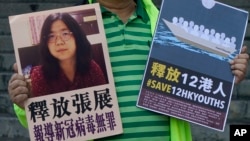 A pro-democracy activist holds placards with the picture of Chinese citizen journalist Zhang Zhan outside the Chinese central government's liaison office, in Hong Kong, Monday, Dec. 28, 2020. 