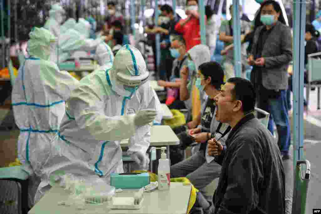 A medical worker takes a swab sample from a resident to be tested for the COVID-19 in Wuhan in China's central Hubei province. Nervous residents of the pandemic epicenter queued up across the city for testing after a new cluster of cases sparked a mass screening campaign.