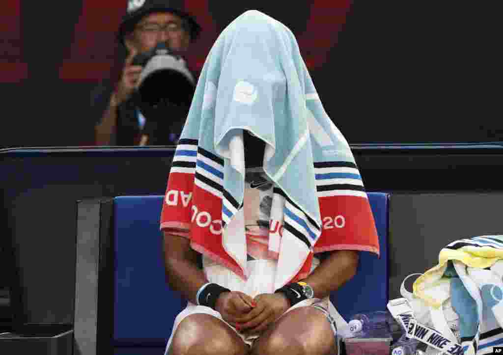 Japan's Naomi Osaka sits with her towel over her head during a break in her third round loss to Coco Gauff of the U.S. at the Australian Open tennis championship in Melbourne, Australia.