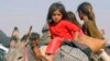 FILE - Displaced children from the minority Yazidi sect, fleeing violence from forces loyal to the Islamic State in Sinjar town, ride on a donkey as they head toward the Syrian border town of Elierbeh, Aug. 11, 2014.