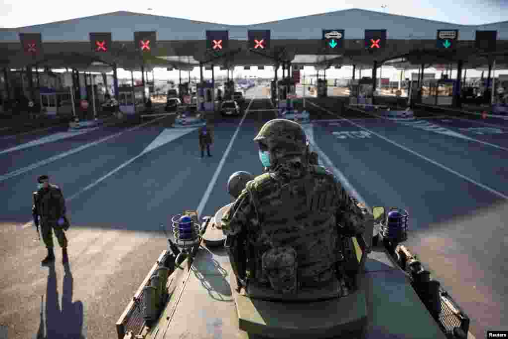 A Serbian army soldier sits on top of armored personal carrier at the Serbia's Batrovci border crossing with Croatia's Bajakovo, as the number of coronavirus cases grow around the world, March 18, 2020.