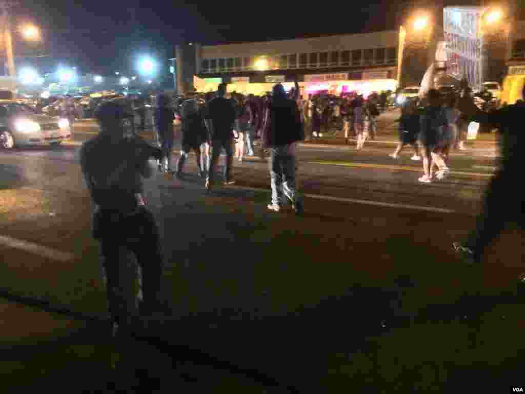 Protesters march past police in Ferguson, Missouri, August 10, 2015. (Kane Farabaugh/VOA News)