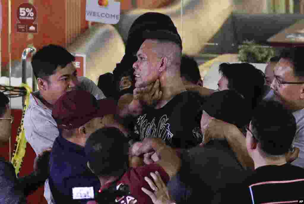 Police subdue hostage taker Archie Paray, center, as he speaks to the waiting media shortly after releasing all his hostages at the V-Mall in Manila, Philippines. Officials say Paray, a recently dismissed security guard, has released his hostages and walked out of the shopping mall, ending a daylong hostage crisis.