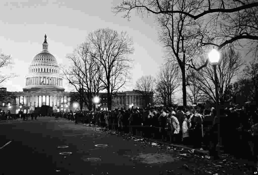Mourners, waiting to view the flag-draped casket of the late President John F. Kennedy in the Capitol rotunda, line the sidewalk as night falls, Nov. 24, 1963.