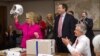 Secretary of State Hillary Rodham Clinton holding up a football helmet presented to her as she returned to work after a month-long absence caused first by a stomach virus, then a fall and a concussion, and finally a brief hospitalization for a blot clot n