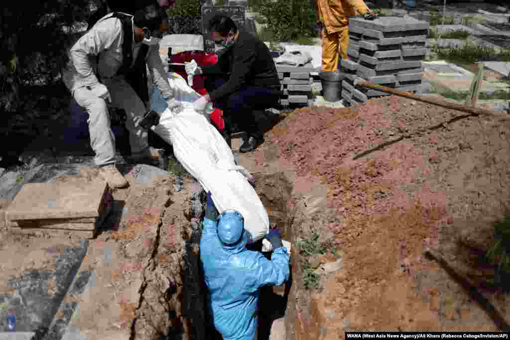 Iranian men bury the journalist Abdollah Zavieh, who passed away due to coronavirus disease (COVID-19), at Behesht Zahra cemetery in Tehran, Iran.