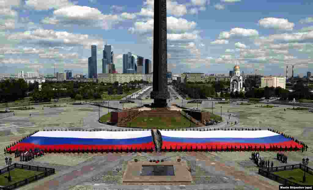 Para kadet dari Kementerian Darurat Rusia memegang bendera terbesar Rusia menjelang perayaan 'Hari Rusia' di Moskow.