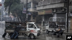 Syrian residents pull a truck that has run out of gas in Aleppo’s Sukari district, Dec. 7, 2012.