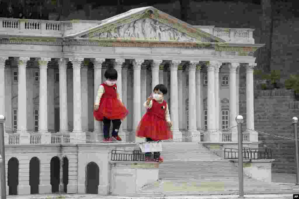 Children wearing face masks stand on the steps of a scaled replica of the United States Capitol Building at the World Park in Beijing, China.