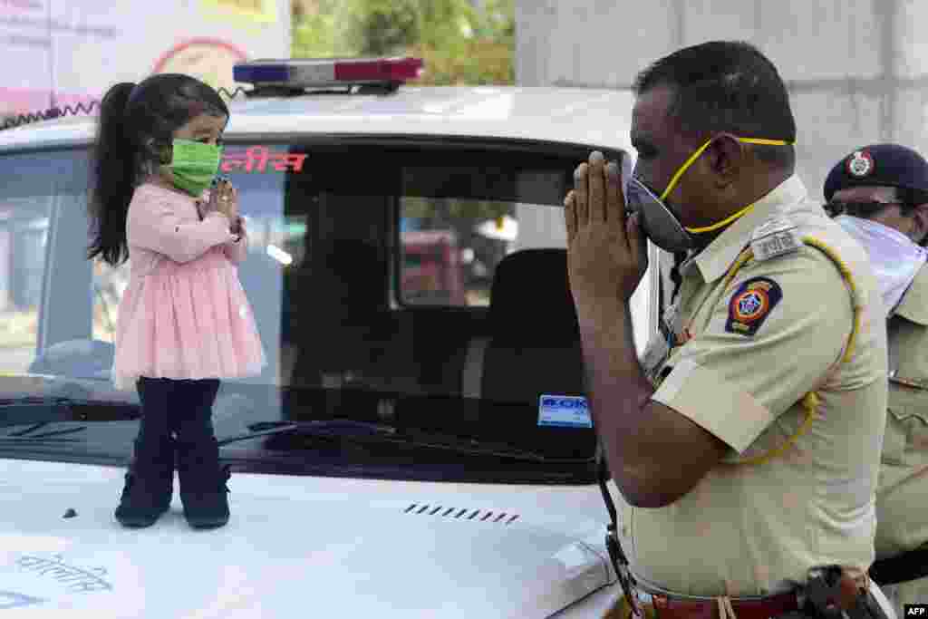 Guinness world record holder of the world's smallest living woman, Jyoti Amge (L), greets a police officer as she appeals citizens to stay inside their homes during a nationwide lockdown as a preventive measure against the coronavirus, in Nagpure, India.