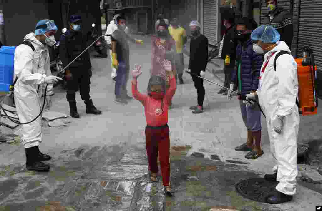 A young Nepalese girl is sprayed with disinfectants as she arrives to get free food distributed by social workers during a lockdown to control the spread of the new coronavirus in Kathmandu.