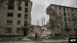 A man rides his bicycle in front of a destroyed apartment building after a Russian strike in the city of Avdiivka, Donetsk Oblast, on March 18, 2023.