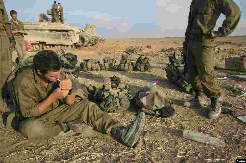 An Israeli soldier smokes a cigarette after crossing back into Israel, July 28, 2014.
