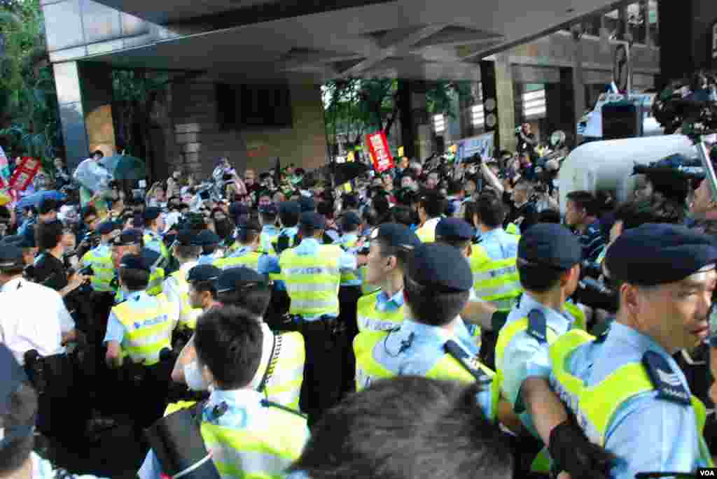 香港警方發射胡椒噴霧阻止示威者衝擊鐵馬,有示威者開雨傘遮擋