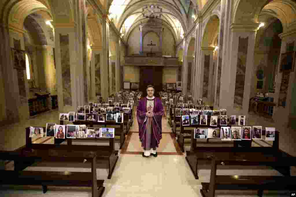 Robbiano Church parson, Don Giuseppe Corbari, poses next to selfies sent by his parishioners and pasted on the pews of the Robbiano church, as Masses for the faithful have been suspended following Italy's coronavirus emergency, in Giussano, northern Italy.