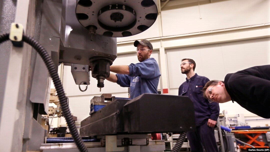 In a photo from Wednesday, Feb. 11, 2015 in Lansing, Mich., Lansing Community College, Brad Bancroft, left, operates a mill as Nate Joseph, center, and Adam Woodhams, right, look on in the advanced precision machining class. (AP Photo/Carlos Osorio)