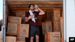 Ethan Hickman utiliza una toalla para secarse el sudor mientras se toma un descanso de descargar un contenedor bajo un calor sofocante, antes de la apertura de un puesto el lunes 17 de junio de 2024, en Weldon Spring, Missouri, Estados Unidos.