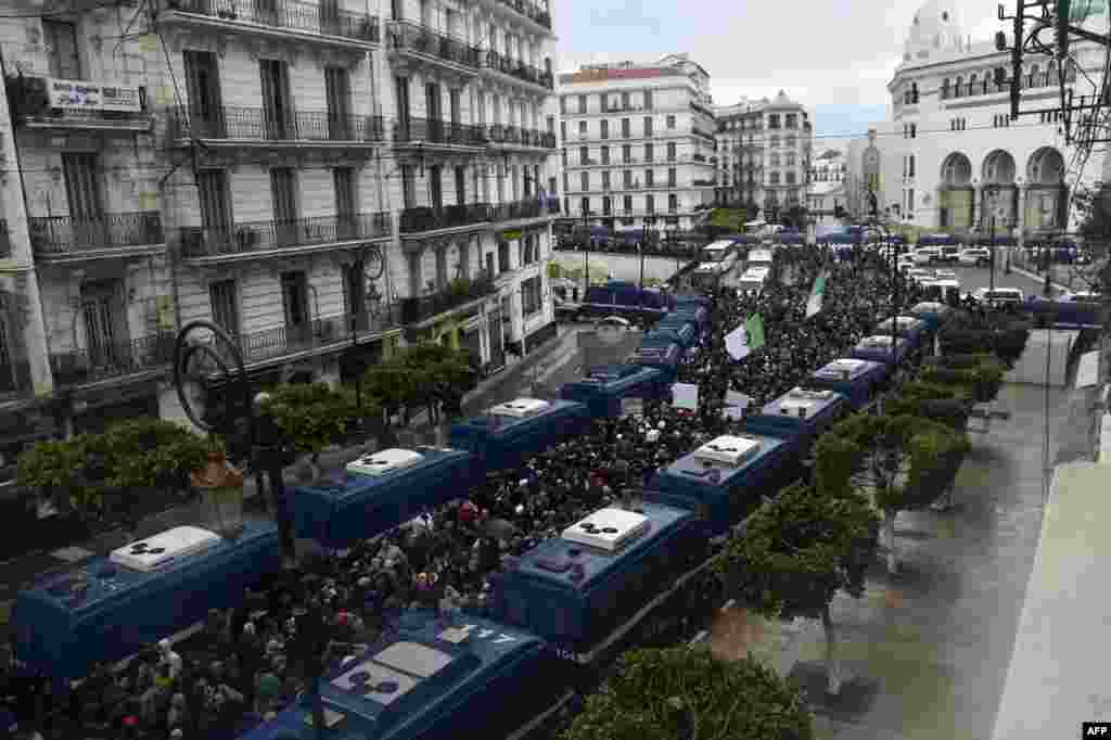 Riot police vehicles are lined up on both sides of a main street in central Algiers as anti-government demonstrators protest in the Algerian capital.
