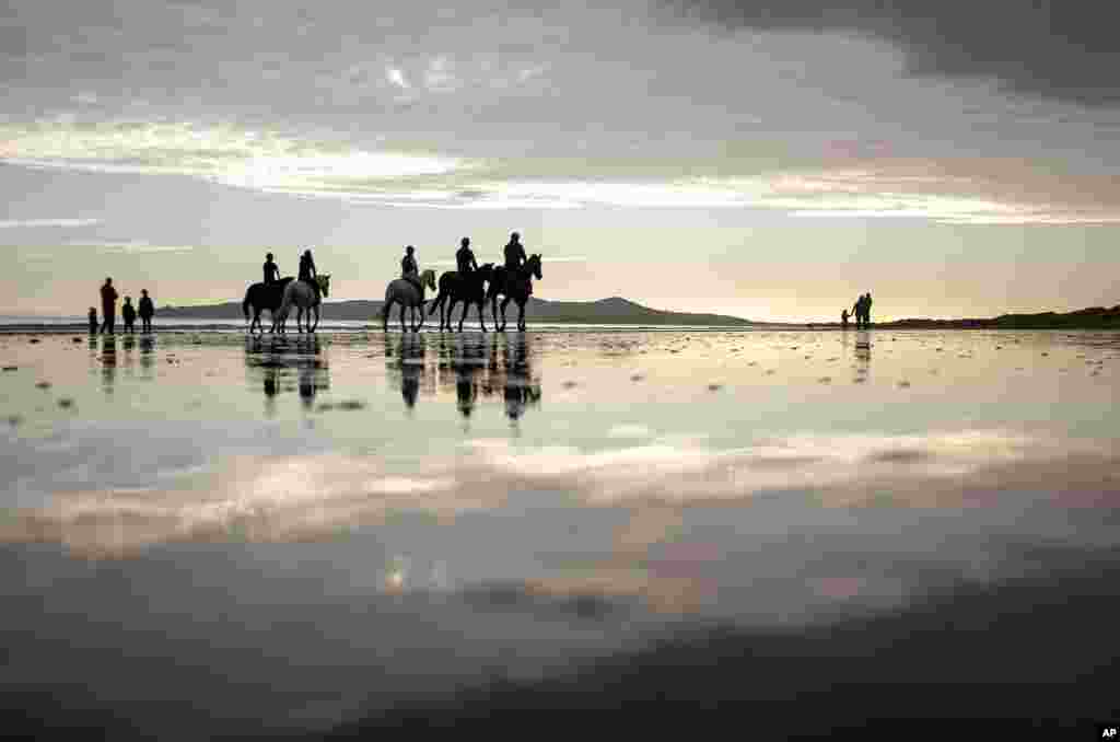 People ride horses along the beach in Portmarnock, County Dublin, Ireland.