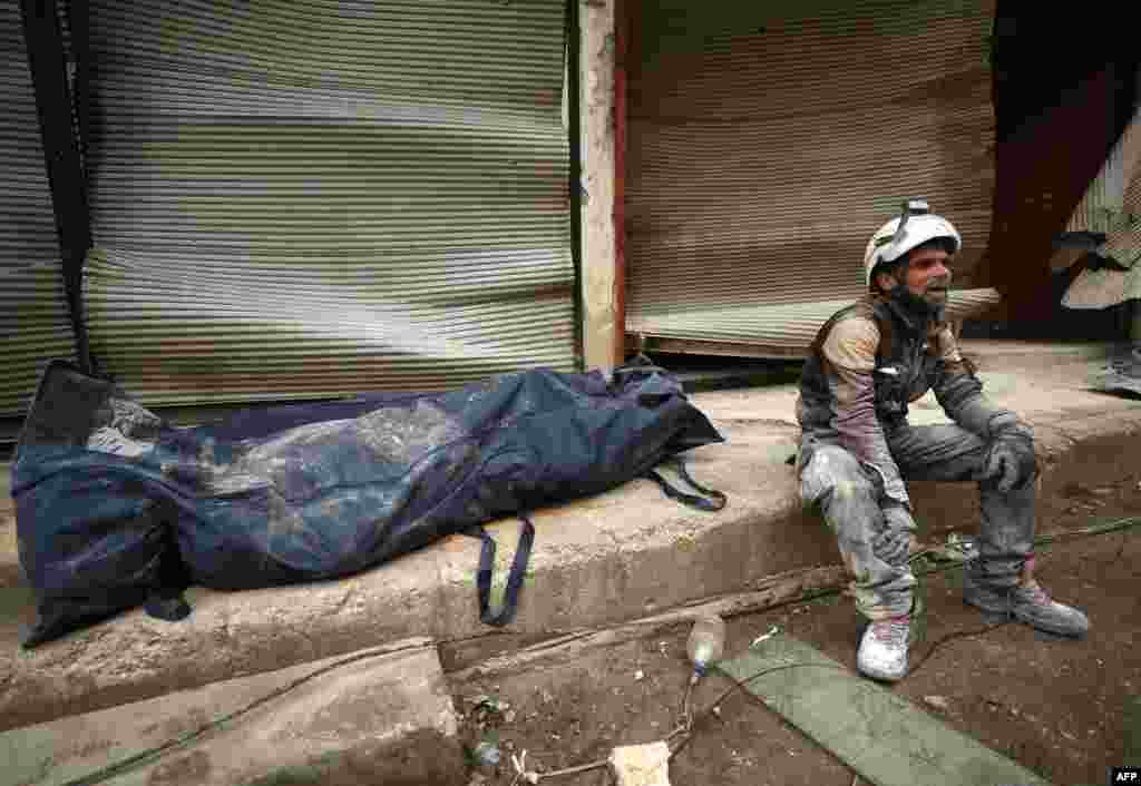 A member of the White Helmets sits next to a body bag containing a victim removed from the rubble of a building, hit during an airstrike by pro-regime forces on the rebel-held town of Ariha in the northern countryside of Syria's Idlib province.