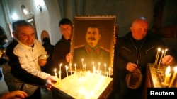 FILE - People place candles inside a church during a gathering to mark the anniversary of Soviet leader Joseph Stalin's death in his hometown of Gori, Georgia, March 5, 2017. 