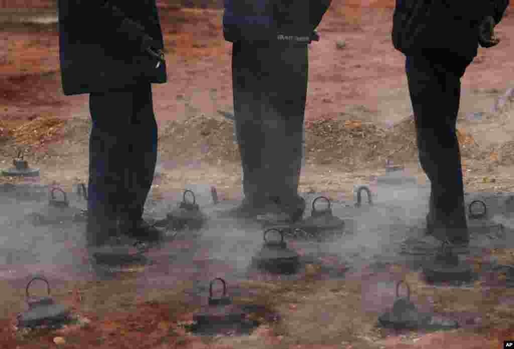 Workers stand over a furnace at a brick factory to keep themselves warm on the outskirts of Kathmandu, Nepal.