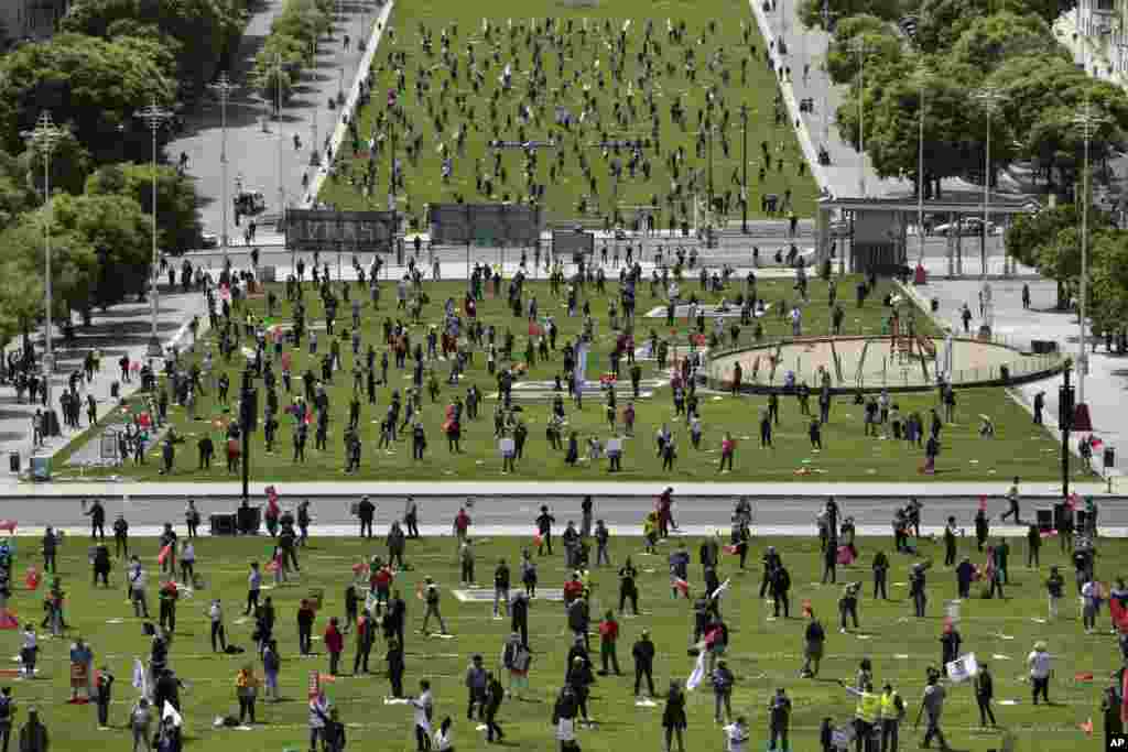 Workers keep a safe distance from each other and wear face masks to help protect against the spread of the new coronavirus during an event marking May Day in Lisbon, Portugal.
