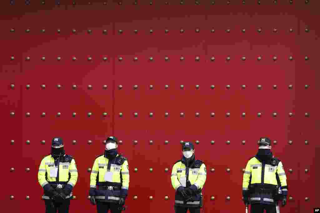 Police officers stand guard as protesters stage a rally calling for a ban on Chinese people entering South Korea in front of the Chinese embassy in Seoul, South Korea.