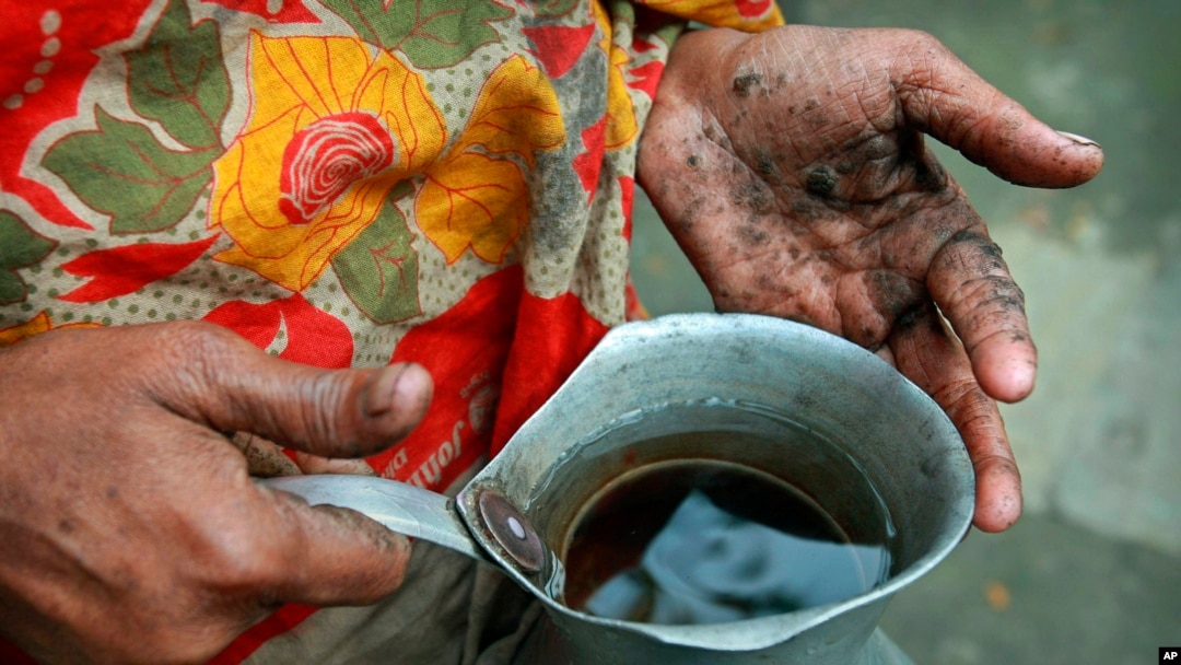 FILE - Hanufa Bibi, 45, holds a can full of contaminated well water, at her village in Chandipur, about 120 kilometers (75 miles) east of Dhaka, Bangladesh, Feb. 22, 2010.