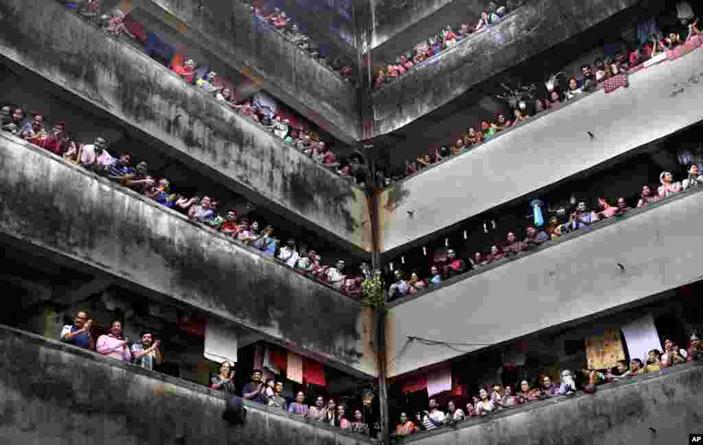 People clap from balconies in show of appreciation to health care workers at a Chawl in Mumbai, India. India observed a 14-hour "people's curfew" called by Prime Minister Narendra Modi in order to stem the rising coronavirus case in the country.