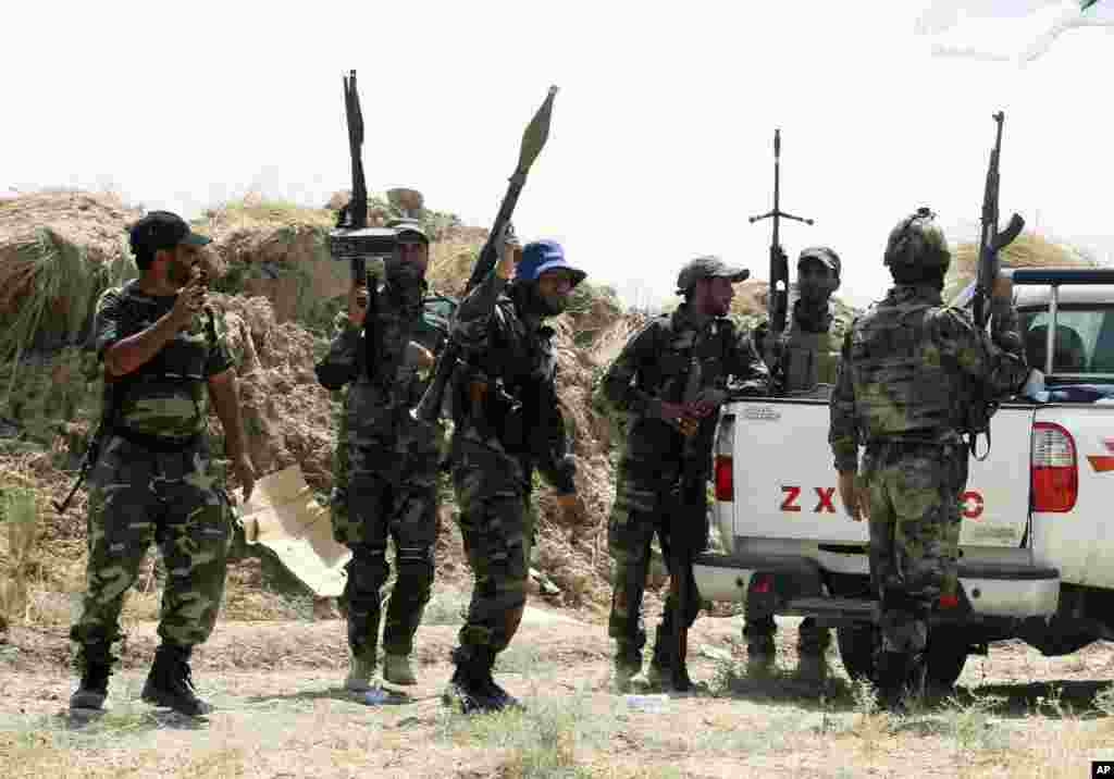 Iraqi security forces and Shiite militiamen stand guard after breaking a siege by the Islamic State extremist group on Amirli, north of Baghdad, Iraq, Aug. 31, 2014.