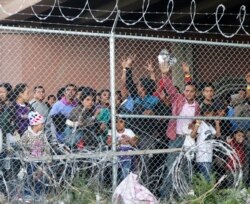 FILE - Central American migrants wait for food in a pen erected by U.S. Customs and Border Protection to process a surge of migrant families and unaccompanied minors in El Paso, Texas, March 27, 2019..