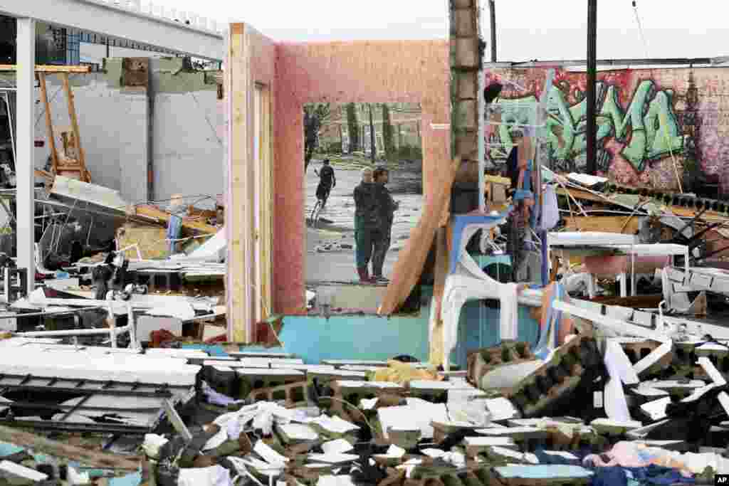 People are reflected in a mirror of a building destroyed by overnight storms in Nashville, Tennessee.