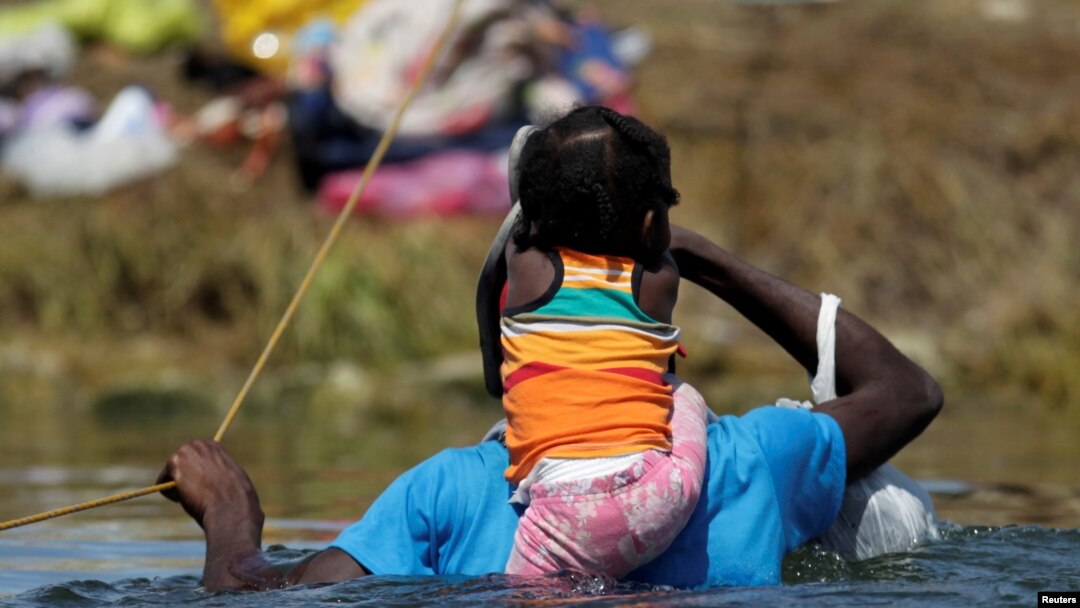 Un migrante con un niño en busca de refugio en EE. UU. atraviesa el Río Bravo desde Ciudad Acuña, México, hacia Del Rio, Texas, EE.UU., el 22 de septiembre de 2021.