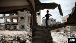 FILE - Palestinian boy plays amid the rubble of his familiy's former house, which was destroyed during the 50-day war between Israel and Hamas militants in the summer of 2014, eastern Gaza City, May 11, 2015.