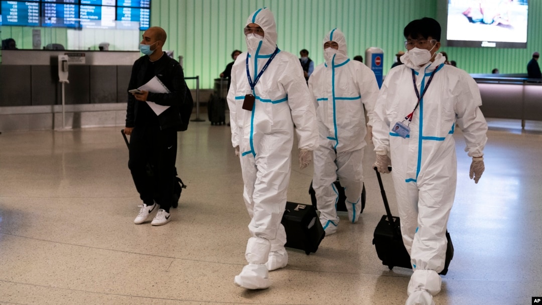 Miembros de la tripulación de vuelo de Air China, con trajes de protección caminan por el área de llegadas en el Aeropuerto Internacional de Los Ángeles en Los Ángeles, el martes 30 de noviembre de 2021.