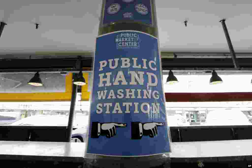 A sign directs visitors to a nearby hand washing station in front of empty vendor booths at the Pike Place Market, March 17, 2020, in Seattle, Washington.